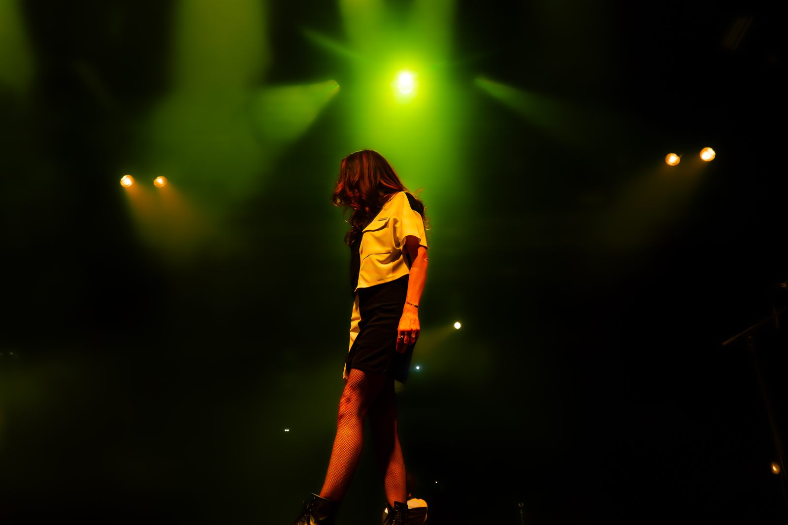 Nelly de profil, en t-shirt jaune, dans une lumière verte